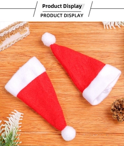 Close-up of mini red Christmas hats for cutlery and wine bottles on a wooden table
