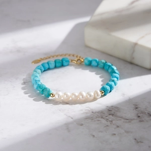 Macro detail of turquoise beaded bracelet with freshwater pearls and golden clasp