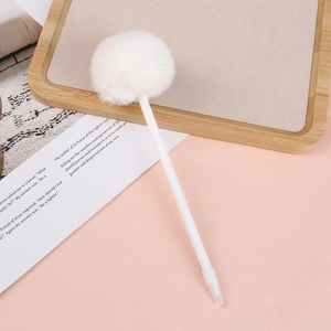 Close-up of white fluffy pom-pom detail on a minimalist pen atop a pink background