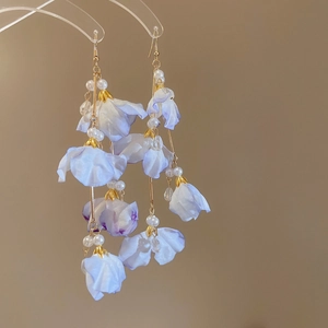 Détail de boucles d'oreilles longues en tissu fleuri avec perles blanches et tiges dorées
