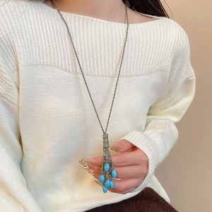 Detail of bohemian long tassel necklace with blue turquoise stone beads on a white sweater