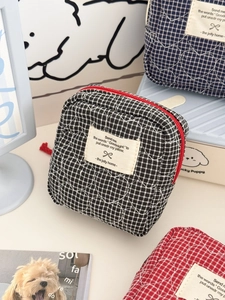 Dettaglio della trapuntatura a cuore e cerniera su tre trousse a quadretti colorati