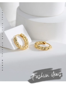 Close-up of gold-plated hoop earrings with hammered texture on a geometric pedestal