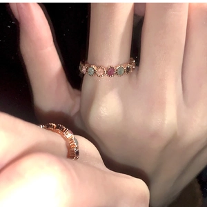 Close-up of rainbow gemstone ring with pink green blue stones in rose gold finish