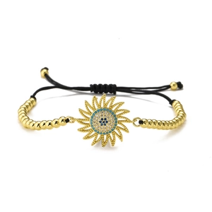 Detail of sunflower evil eye charm with blue zircon on adjustable gold beaded bracelet