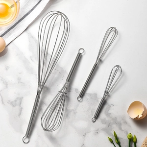 Set of 4 stainless steel spring handle whisk mixers on marble kitchen countertop