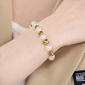 Bracelet élégant en perles d'eau douce et billes dorées porté sur un blazer