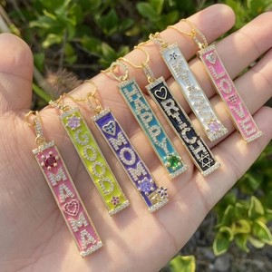 Handheld view of seven rectangular 18K gold plated zircon pendants with colorful enamel
