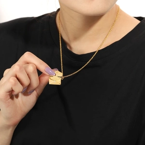 Detailed view of an openable gold envelope locket pendant with 'Love' engraving