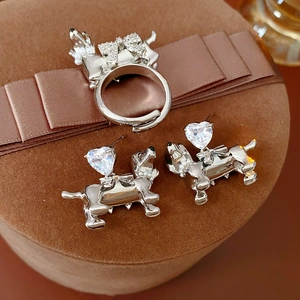 Close-up of silver dachshund ring and heart zircon earrings on brown velvet gift box