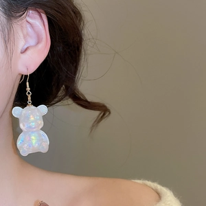 Close-up of holographic white resin bear earrings worn by a model in soft lighting