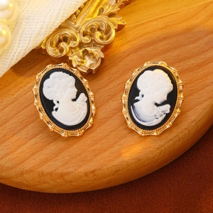 Close-up of vintage cameo earrings with white female portrait on circular wood base