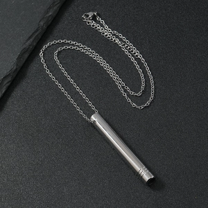 Silver stainless steel mindfulness breathing whistle necklace on dark textured stone