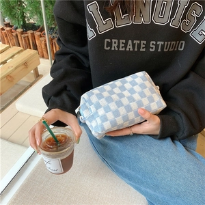 Blue and white checkered knit pouch held by model in a casual lifestyle setting