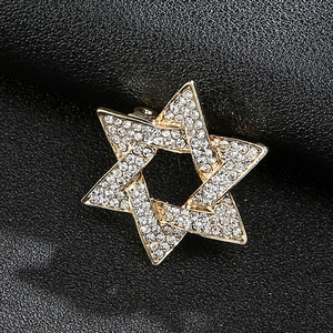 Detailed close-up of a golden hexagonal star brooch with sparkling crystals on black leather