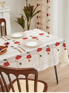 Detail of red poinsettia floral embroidery and lace edges on a cream linen tablecloth