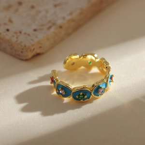 Macro detail of gold open ring featuring blue enamel circles and vibrant colorful gemstones