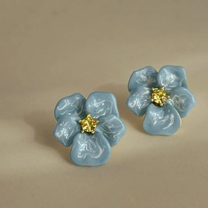 Macro de boucles d'oreilles fleurs bleues marbrées avec une pierre jaune au centre