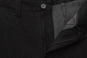 Dettaglio di pantaloni in denim nero con cerniera, bottone e trama del tessuto twill