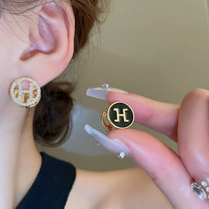 Close-up of the micro-paved crystal and black enamel H-logo round stud earring details