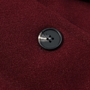 Close-up of burgundy wool coat fabric with a premium marble-textured black button