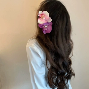Elegant floral hair claw clips with pearls shown on model in a soft vacation style