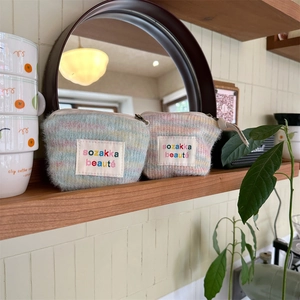 Close-up of soft striped plush cosmetic bags with zip closure on a wooden shelf