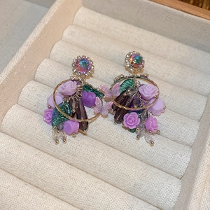 Détail de boucles d'oreilles fleurs en cristal violet dans un écrin en velours