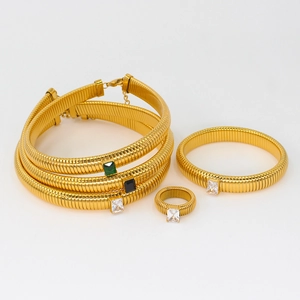 Detail of gold jewelry set with emerald, black, and white gems and textured snake chain