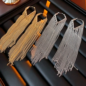 Detailed close-up of long metal tassel earrings in gold and silver finishes on a tray