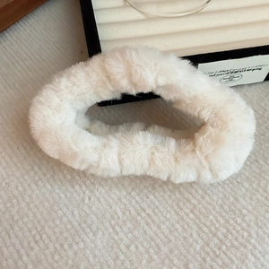Detail shot of white plush faux fur cross hair claw clip on white textured background