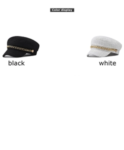 Detail of tweed fiddler caps in black and white with decorative gold chain accents