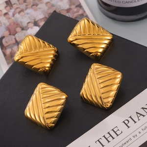 Boucles d'oreilles carrées minimalistes dorées texturées sur une surface en cuir