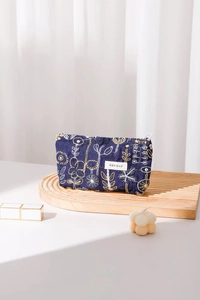 Close-up of floral embroidery on navy blue cotton linen makeup bag with H & R logo
