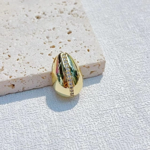 Polished gold egg-shaped pendant with vertical diamond inlay on a stone surface