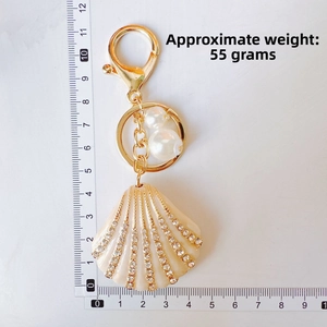 Detail view of rhinestone-studded seashell keychain with pearls and measuring ruler