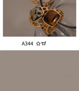 Detail view of gold chain rings featuring square tiger eye and spotted natural stones