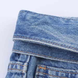 Gros plan sur un short en jean bleu délavé avec doubles coutures orange et sergé fin