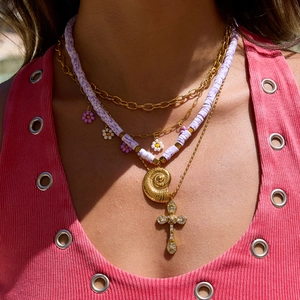 Gros plan de colliers multicouches en acier doré 18K avec perles mauves et pendentif coquillage