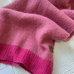 Close-up of soft pink cashmere-like knit scarf featuring a brown FUM brand label
