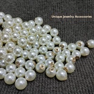 Macro detail of glossy ABS imitation pearls with gold metal caps on a textured surface