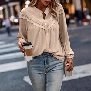 Detailed close-up of delicate lace embroidery and V-neckline on apricot long sleeve blouse