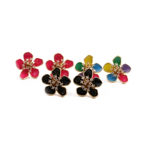 Dettaglio degli orecchini a fiore placcati oro con petali in smalto e cristalli centrali