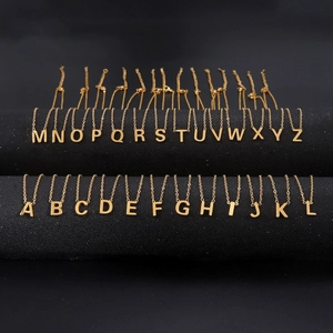 Gold stainless steel 26 initial letter pendant necklaces displayed on black stands