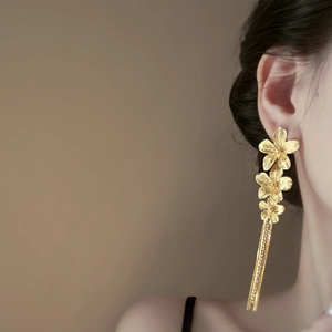 Elegant gold flower tassel earrings featuring brushed metal petals and long fringe