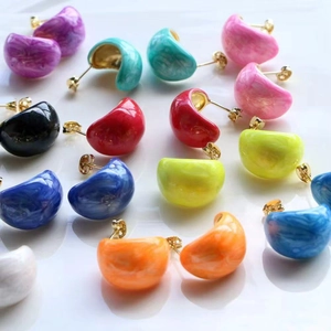 Macro shot of colorful C-shaped enamel earrings with marble texture and gold accents