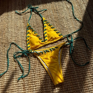 Detail of yellow bikini top featuring metal eyelets and green crisscross lace-up design
