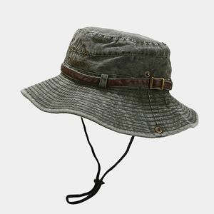 Dettaglio di cappello outdoor in tela lavata con fibbia in pelle e ricamo di montagna