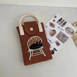 Close-up of brown knitted phone bag with black cat design and faux leather handle