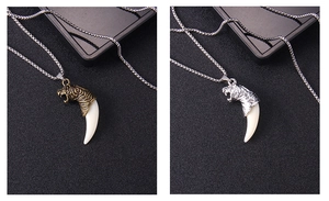 Detail of vintage wolf tooth pendants in bronze and silver finishes with tiger head design